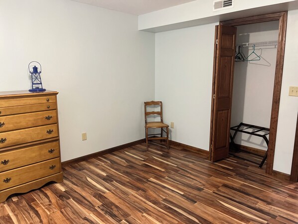 A room with a wooden dresser, a chair, and a closet with hangers. - The Boatyard Loft and Suites Unit B (Sandusky)