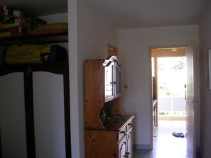 Una cocina con armarios de madera, una encimera y una puerta que da a un espacio exterior luminoso.