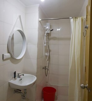 Bathroom features a sink, mirror, shower area with showerhead and curtain, and a tiled floor.