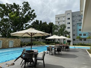 Relax by the serene pool surrounded by lush greenery and comfortable lounge seating.