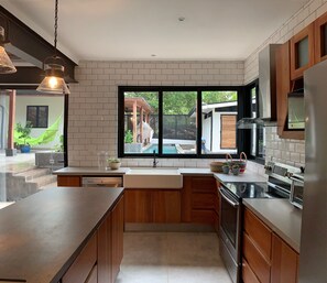 Una cocina moderna con un ventanal grande, armarios de madera, horno empotrado y un lavamanos.