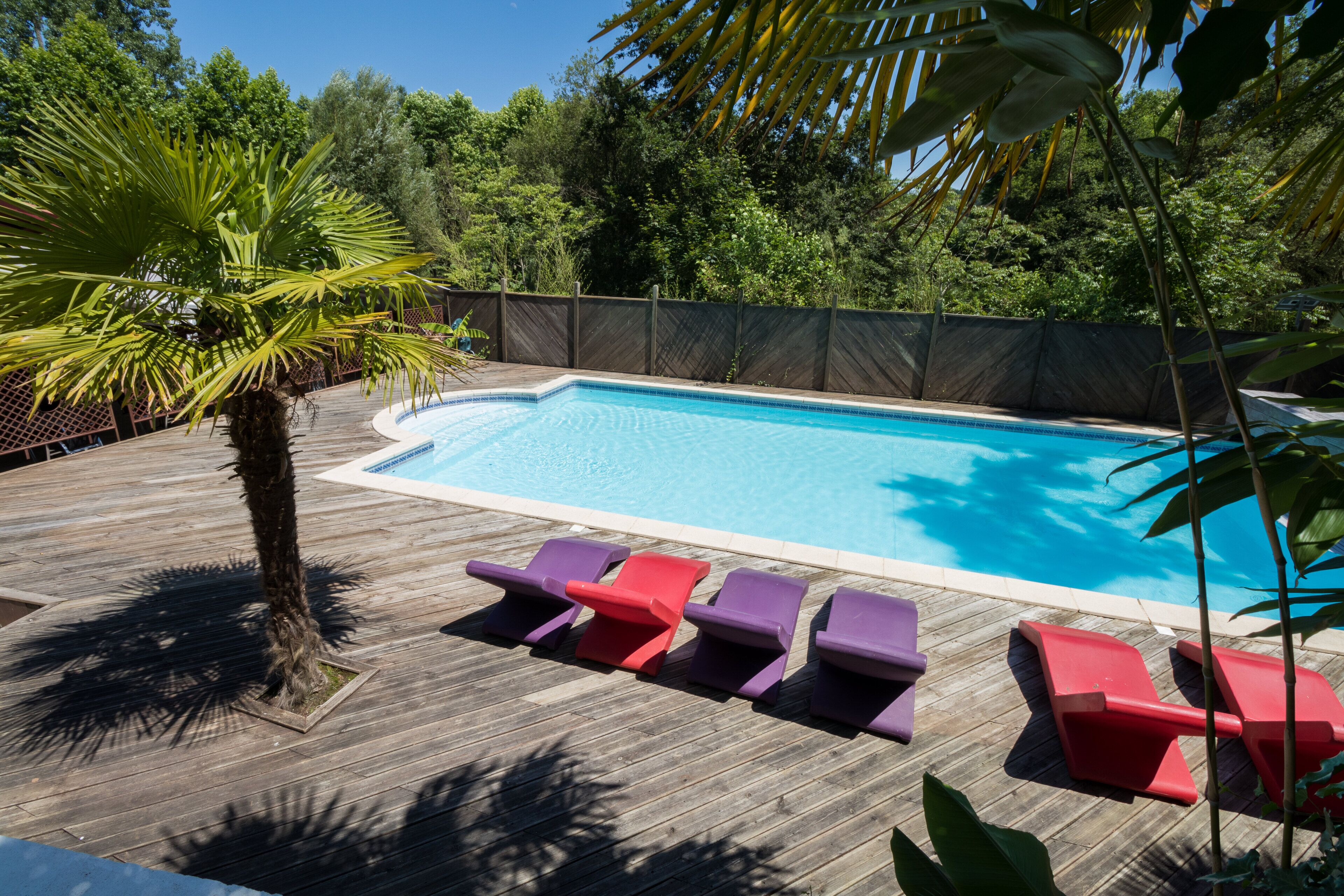 Eine Holzterrasse mit Pool, umgeben von einem Zaun und Bäumen.