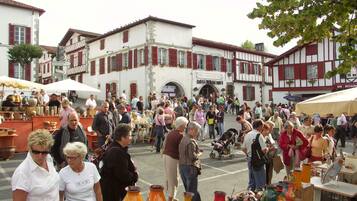 Un marché animé en plein air, où les gens flânent et les vendeurs proposent de la poterie.
