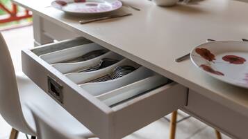 Una mesa de comedor con un cajón que contiene utensilios.