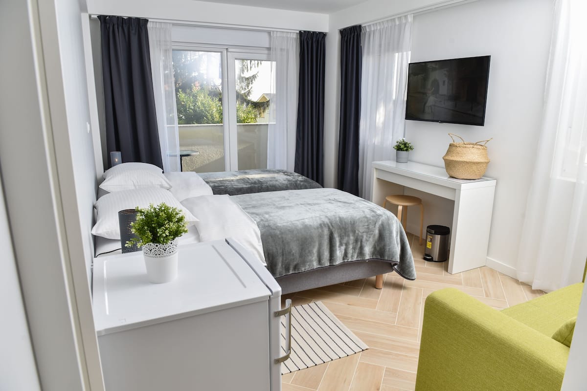 Ein modernes Hotelzimmer mit Bett, Schreibtisch, Fernseher und Blick ins Freie.