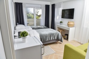 A modern hotel room with a bed, a desk, a TV, and a view of the outdoors. - Rooms At Zajceva 34 (Zagreb)