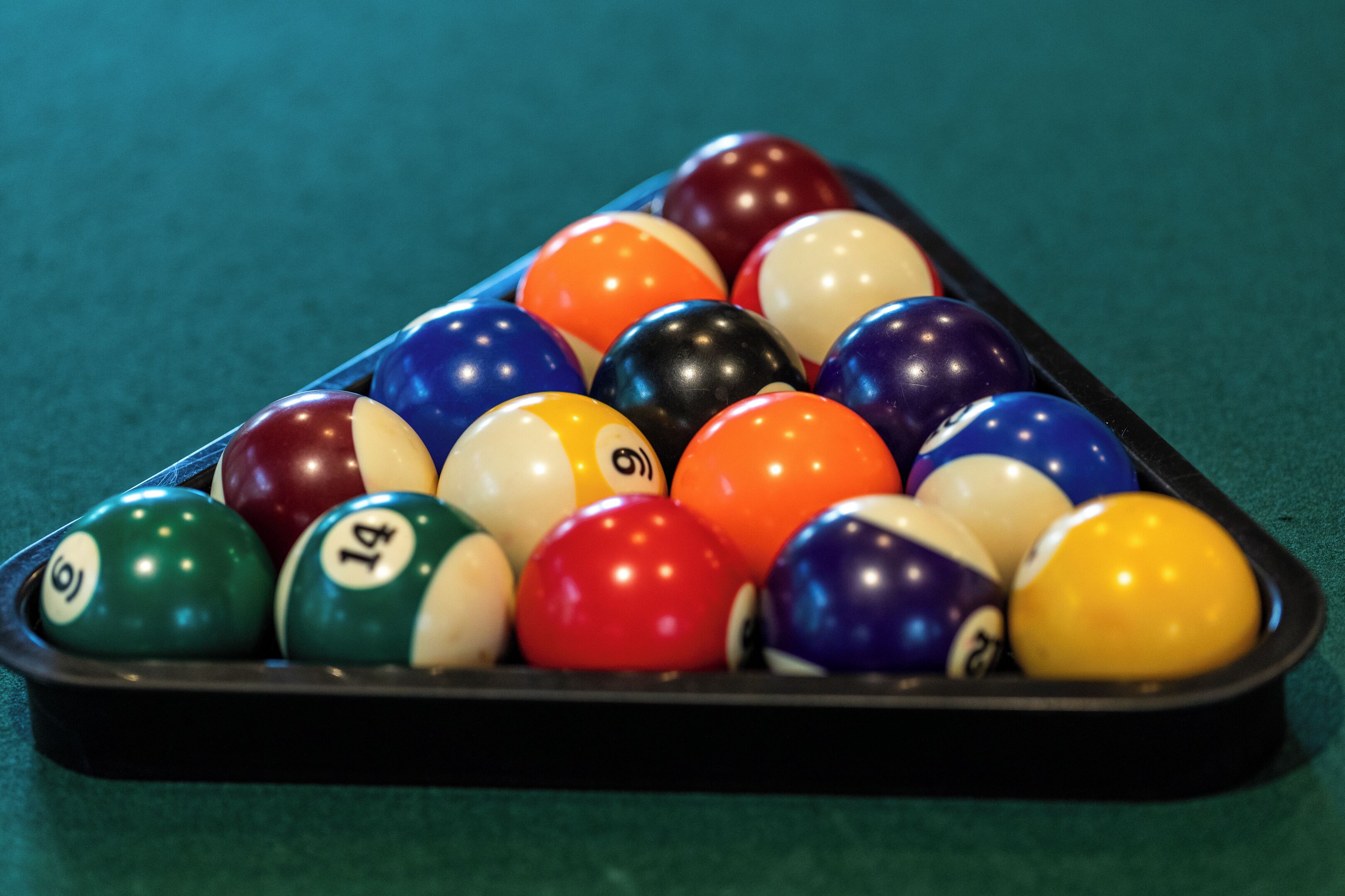 A pool table with a triangular rack of billiard balls.