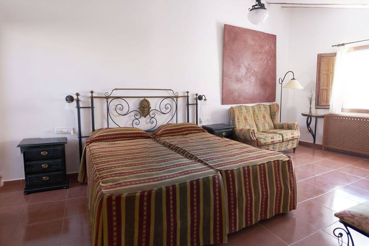 Une chambre à coucher avec un lit double, une chaise, une petite table et une lampe.