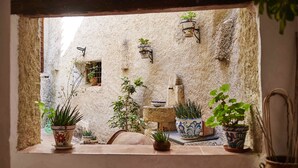 Un interior rústico con pared de piedra, plantas en macetas y un ventanal pequeño.
