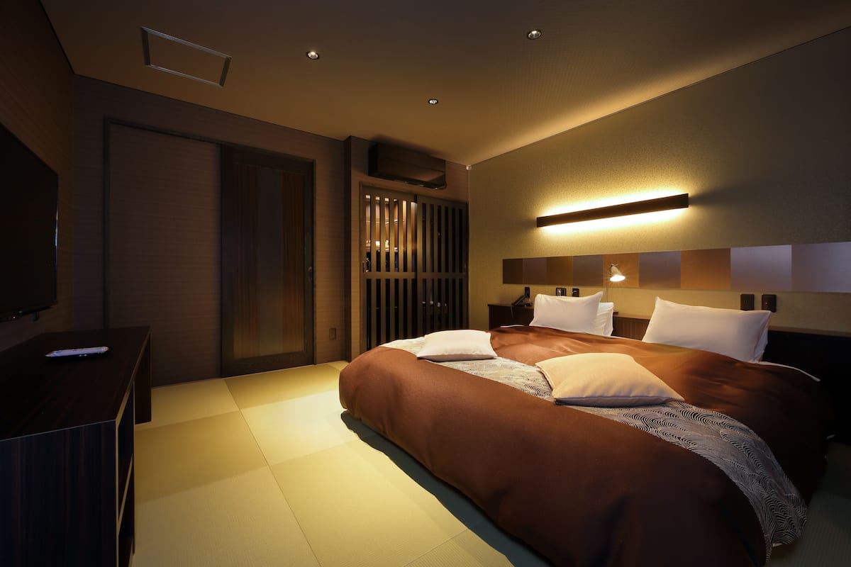 A modern hotel room with a large bed, a flat-screen TV, and a bedside table.