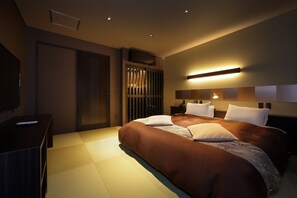 Una habitación de hotel moderna con una cama grande, un televisor de pantalla plana y una mesita de noche.