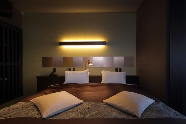 A hotel room with a large bed, two bedside tables, a wall-mounted light, and a headboard with a light panel.