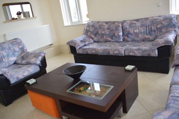 A living room with a patterned sofa, a coffee table with a bowl, and a small table with a box.