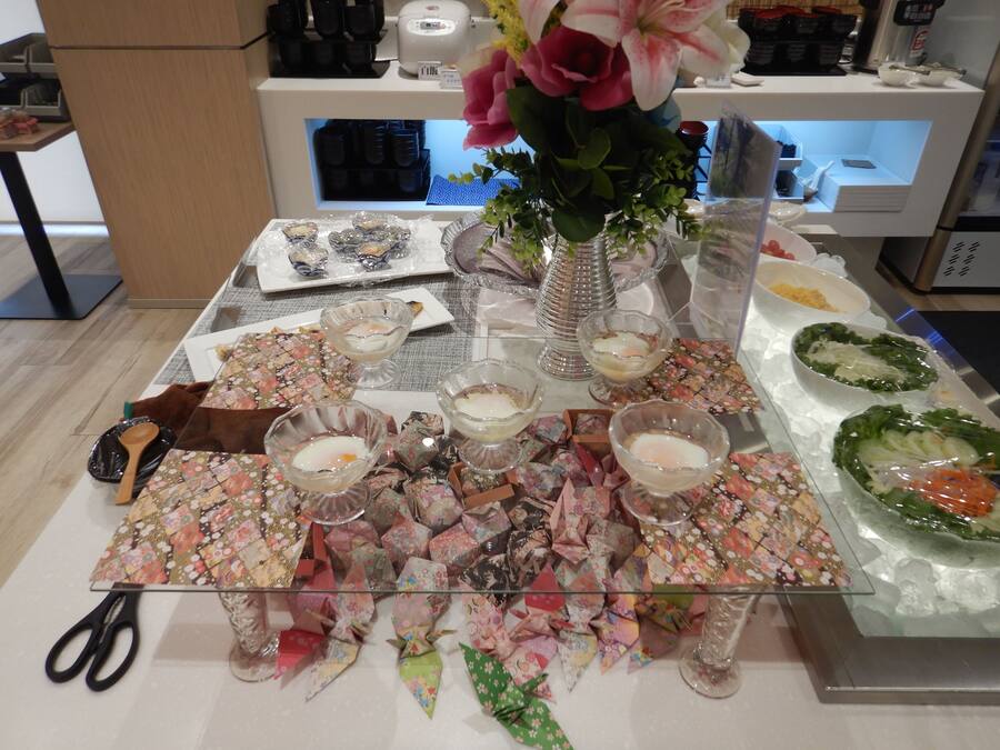 Een tafel met origami-decoraties, een vaas met bloemen en diverse etenswaren.