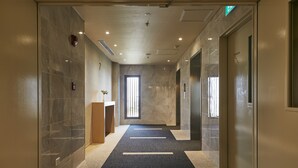 A modern hotel corridor with marble walls, a carpeted floor, and a wooden reception desk. - Wishton Hotel Yangon (Yangon)
