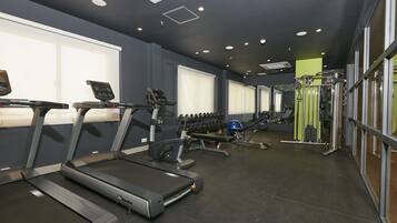 Un gimnasio con cintas de correr, mancuernas y máquinas de pesas.