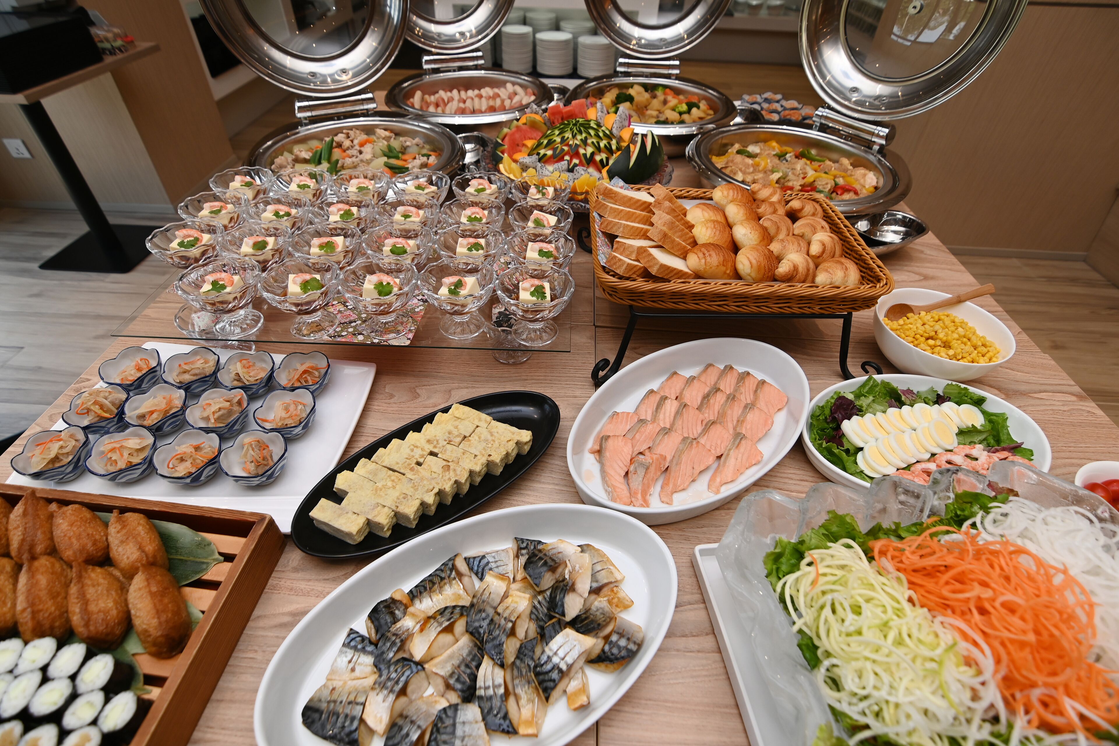 A buffet with various dishes including sushi, sashimi, and bread.