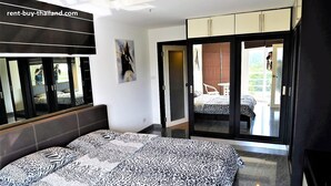 Ein Schlafzimmer mit einem Bett, einem großen Spiegel, einer Tür, die auf einen Balkon führt, und einem Bild an der Wand.