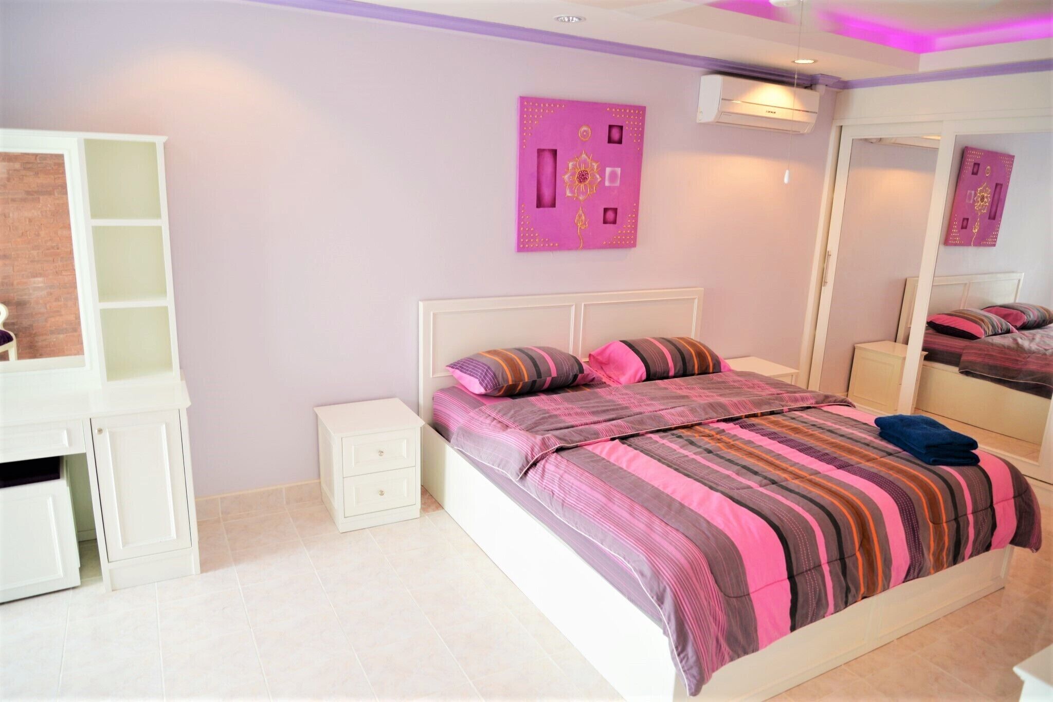 A bedroom with a bed, a nightstand, a dresser, and a mirror.