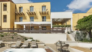 A hotel with a pool area, outdoor seating, and a staircase leading to an upper level. - Luna del Raccolto (Valderice)
