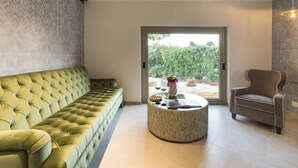 A modern living room with a green sofa, a round coffee table with decorative items, and a brown armchair. - Luna del Raccolto (Valderice)