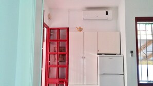 Une cuisine de taille réduite, équipée d’un réfrigérateur, d’un placard blanc et d’une porte rouge.