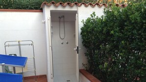 Un petit espace douche fermé, doté d’un sol carrelé et d’une porte blanche.