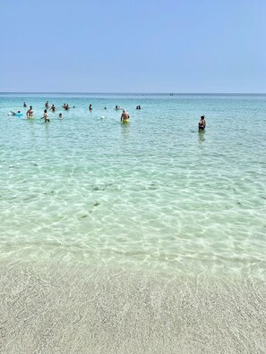 Ein Strand mit klarem, flachem Wasser und einem Sandufer.