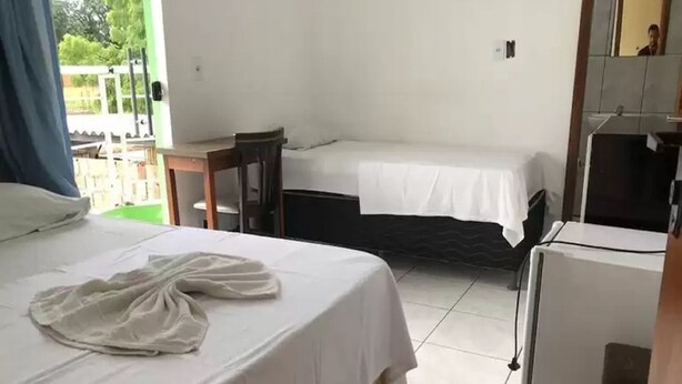 A hotel room with two beds, a small table, a chair, and a refrigerator. - Hotel Canto D'Oeste (Barreiras)