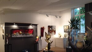 Een kunstgalerie met diverse beelden en schilderijen die op muren en tafels staan uitgestald.