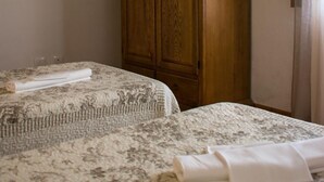 Un dormitorio con dos camas, un armario de madera y una cortina.