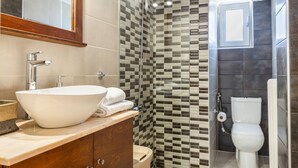 A modern bathroom with a large vessel sink, a shower enclosure, and a toilet. - Mirsini's Apartment in Chania Center (Chania)