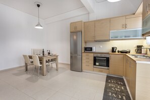 A modern kitchen with wooden cabinets, stainless steel appliances, and a dining area with a table and chairs.