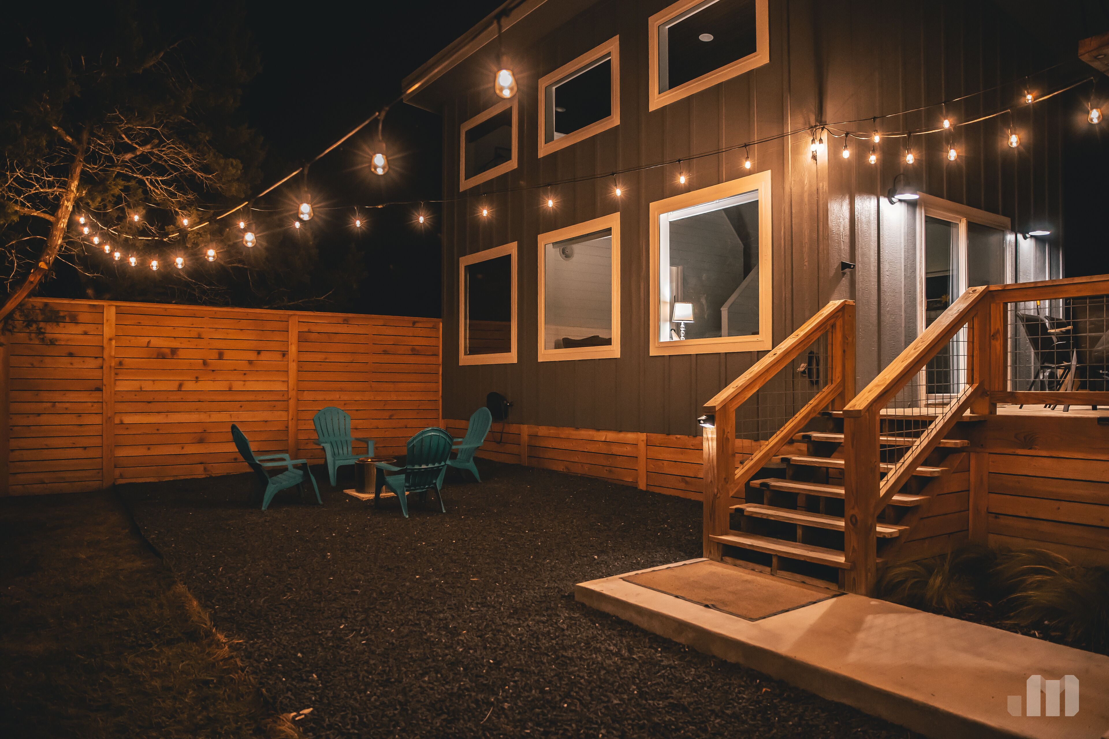 A wooden house with a covered porch, a staircase, and string lights.