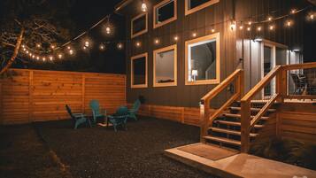 A wooden house with a covered porch, a staircase, and string lights.