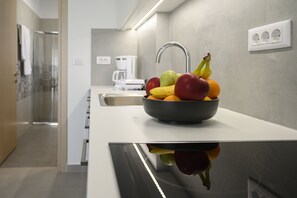 A modern kitchen with a fruit bowl on the counter, a coffee maker, and a sink.