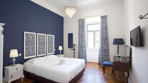 Une chambre à coucher avec un grand lit, des tables de chevet, une commode, un miroir et un lustre.
