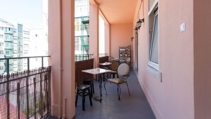 Un balcon avec une table et des chaises, une fenêtre et une vue sur les bâtiments.