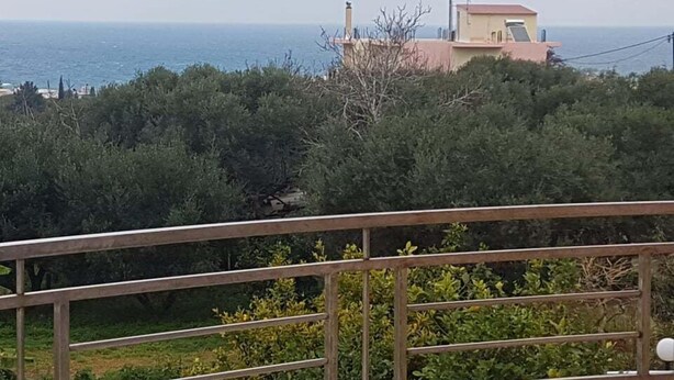 A balcony with a view of the sea and a building in the background. - Ria's Sea View Apartment (Chania)