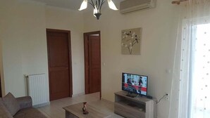 A living room with a TV, a sofa, a coffee table, and a chandelier. - Ria's Sea View Apartment (Chania)