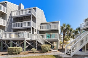 A multi-story building with balconies, staircases, and a clear blue sky.