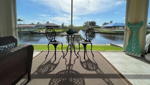 Eine Terrasse mit zwei Stühlen und einem Tisch, mit Blick auf einen Kanal und Häuser im Hintergrund.