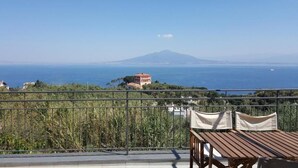 Ein Balkon mit Blick auf das Meer und ein Berg in der Ferne.