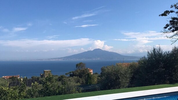 Ein Schwimmbecken mit Blick auf einen Berg und das Meer.