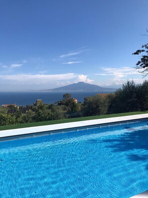Ein Schwimmbecken mit Blick auf einen Berg und das Meer.