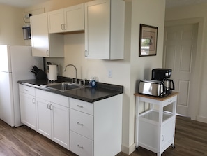 A kitchen with white cabinets, a double sink, a coffee maker, and a small cart. - #17 Isle View - Fishing, Sunsets, Beaches, Golfing (Alburg)