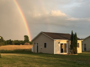 A single-story house with a front door, a small porch, and a tall tree beside it. - #17 Isle View - Fishing, Sunsets, Beaches, Golfing (Alburg)