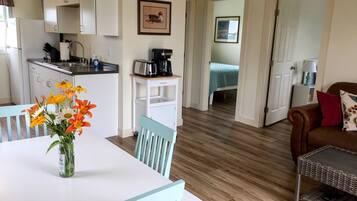 Een compacte woonruimte met een kitchenette, een eethoek met een tafel en stoelen, een bank en een bed in de aangrenzende kamer.