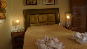 A hotel room with a large bed, two bedside lamps, and artwork on the wall. - Zoi's Holidays Apartment (Platanias)
