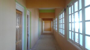 Un pasillo largo y estrecho con puertas a un lado y ventanas al otro.